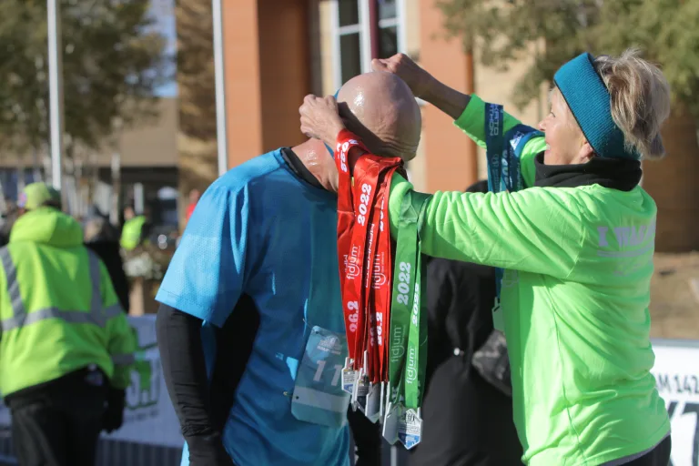 Woman putting a finisher's medal on a man