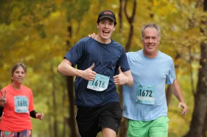 two men and a woman running and smiling at the camera